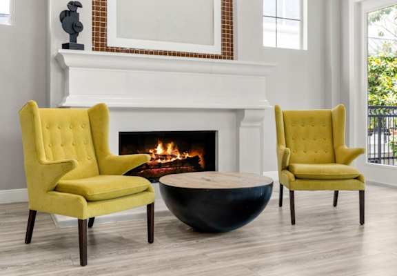 Two yellow chairs are placed in front of a fireplace.