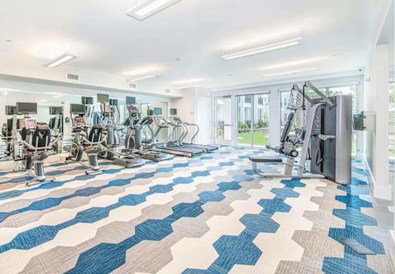 A gym with a variety of equipment including treadmills, weights, and exercise machines.