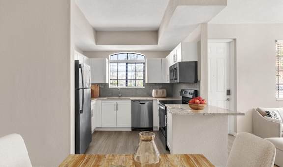 A modern kitchen with white cabinets and a wooden table at San Mareno at Mirasol.