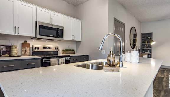 A kitchen with a white countertop and a sink.