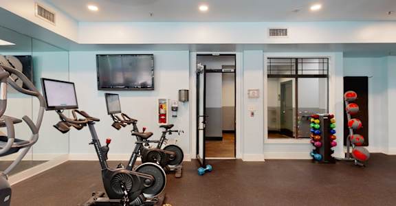 A gym with exercise equipment and a television.