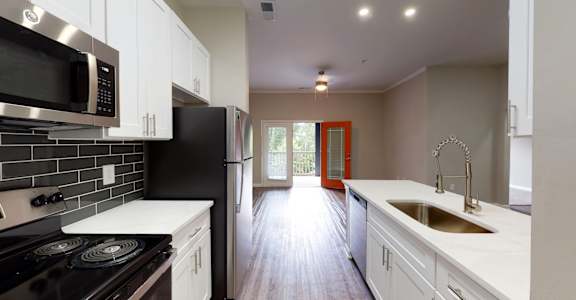 A kitchen with black and white appliances and a red door. at Vue at Embry Hills, Georgia