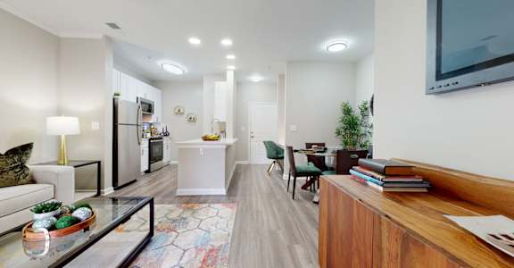 A modern living room with a glass coffee table and a wooden bookshelf.