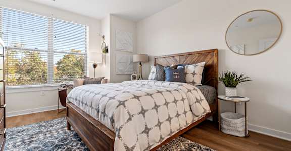A bedroom with a large bed and a window with blinds.