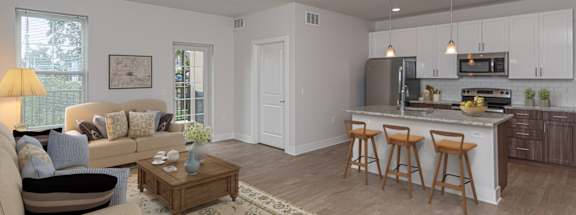 A well-lit, modern kitchen with a breakfast bar and a living room area with a sofa and coffee table.