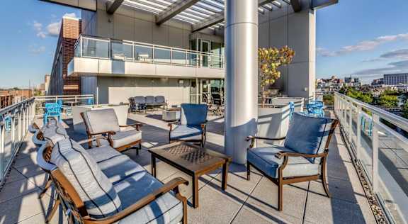 A patio with chairs and a table is set up on a balcony.