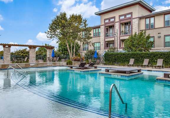 A pool area with chairs and a table.