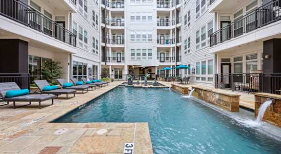 A large indoor swimming pool with a waterfall and lounge chairs.