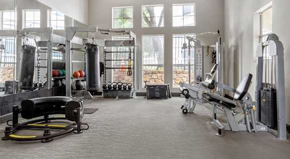 A gym with a variety of equipment including a weight bench, a rowing machine, and a punching bag.