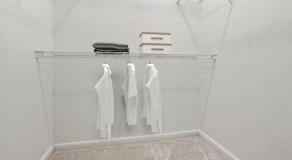 A white laundry room with clothes hanging on a rack.