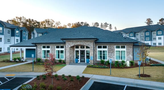 A building with a grey roof and a blue door is surrounded by a parking lot. at Fairview Springs in Covington, GA, 30016