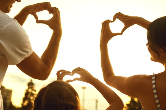 a man and woman making a heart shape with their hands