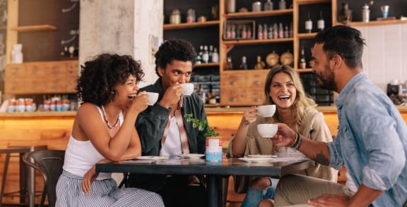 group of people sitting at a table drinking coffee