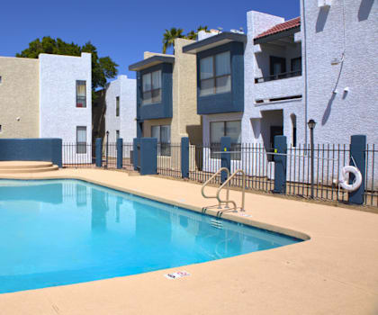 A swimming pool in front of a row of houses.