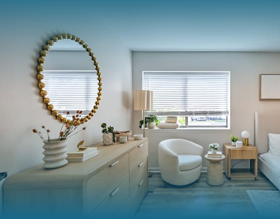 A bedroom with a bed, chair, and a mirror.
