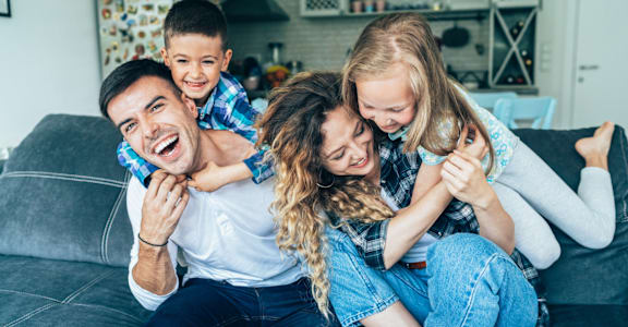a family of four sitting on a couch with their arms around each other