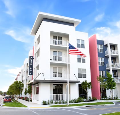 A white building with a red and blue stripe on the side and an American flag hanging from the balcony.