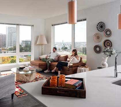 two people sitting in a living room with a kitchen