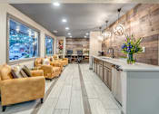 Thumbnail 20 of 27 - Resident lounge with kitchenette and decorative pendant lights at The Colony Apartments, Universal City, TX