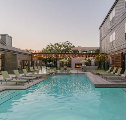 a pool with lounge chairs and umbrellas at dusk