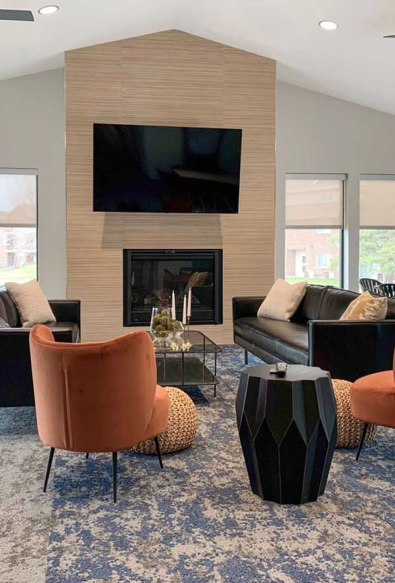 a clubhouse living room with couches and chairs and a fireplace