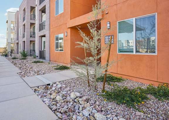 A modern apartment building with a sidewalk and landscaping in front.at Cottonwood Ranch, Casa Grande