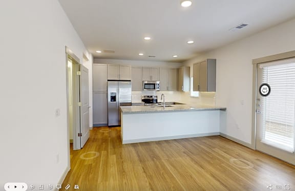 A modern kitchen with wooden floors and white walls.