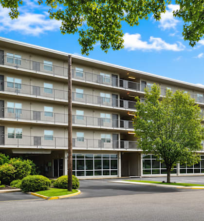 A large apartment building with a parking lot in front.