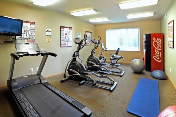 a gym with cardio equipment and a coke machine