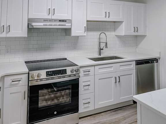 A modern kitchen with white cabinets and a black oven.