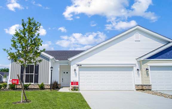 A house with a white garage door and a tree in front.
