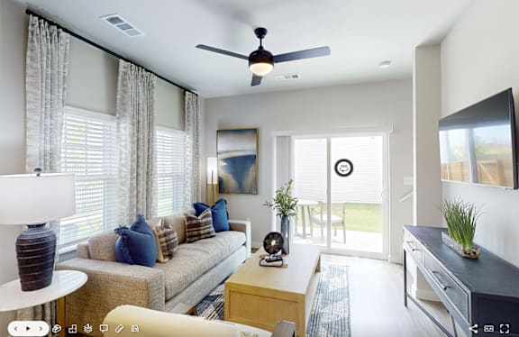 A living room with a couch, a coffee table, and a ceiling fan.