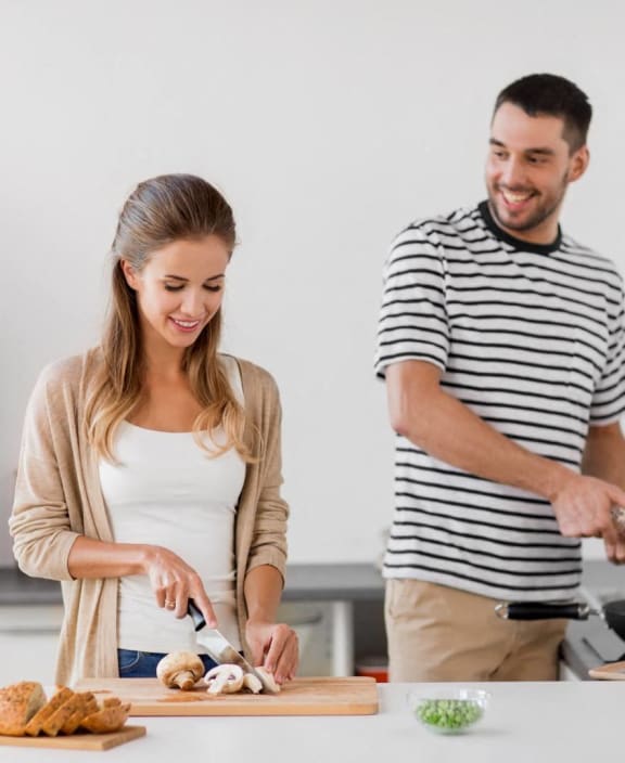 a man and woman in a kitchen preparing food at Sandhill Parkway Townhomes Apartments, East Bethel, Minnesota