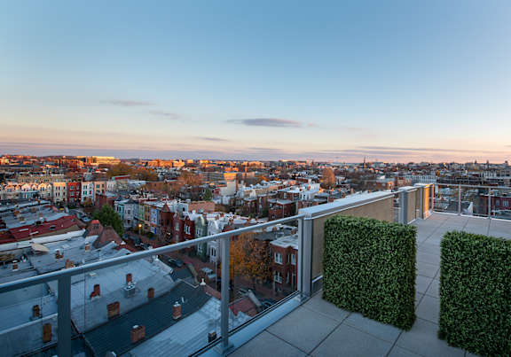 A balcony overlooks a cityscape at sunset.