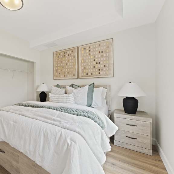 a bedroom with a bed and a nightstand with a lamp and flowers