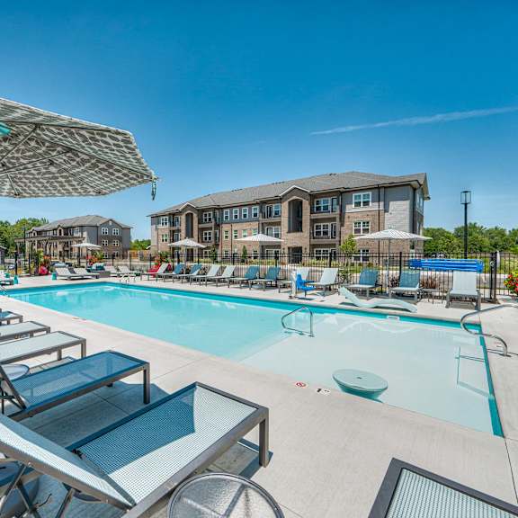 A sunny day at the pool with lounge chairs and umbrellas.