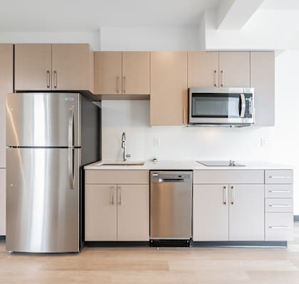 A modern kitchen with a stainless steel refrigerator, microwave, and cabinets.