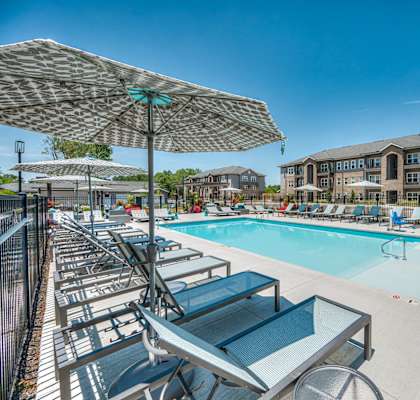 A sunny day at the pool with lounge chairs and umbrellas.