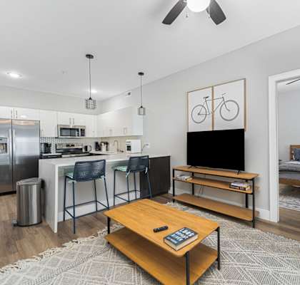 A modern living room with a kitchen area in the background.