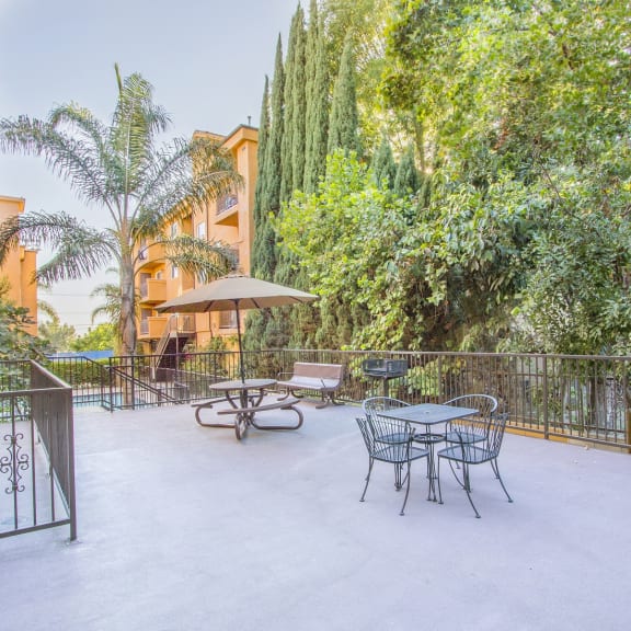 a patio with a table and chairs and trees in the background at Dronfield Astoria Apartments, Sylmar, California, 91342