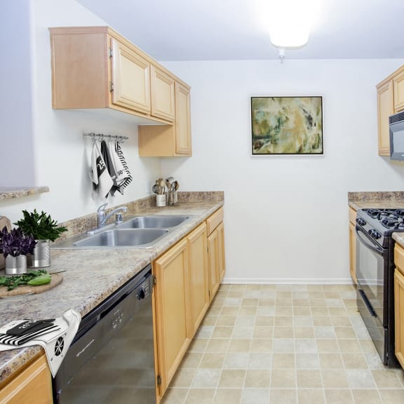 a kitchen with wooden cabinets and stainless steel appliances at Dronfield Astoria Apartments, Sylmar, California, 91342