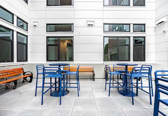 A patio with blue chairs and orange benches.