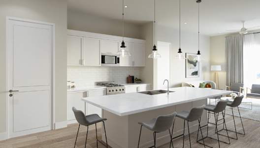 A modern kitchen with a long white island and grey chairs.
