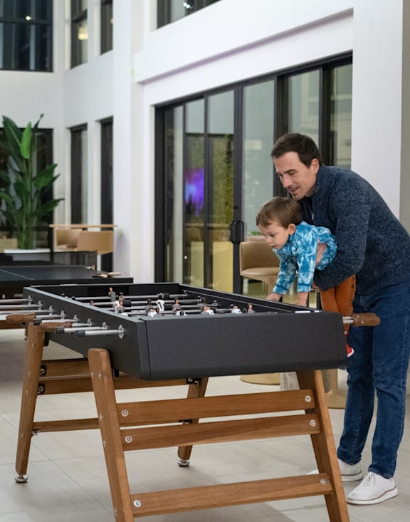 A man and a child are playing air hockey together.