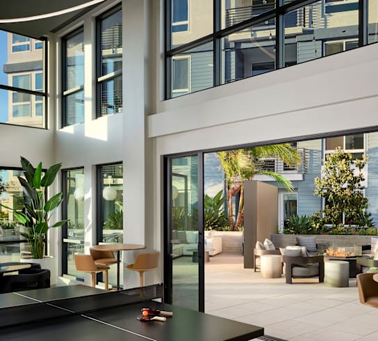 A ping pong table is in the middle of a spacious room with a view of the outdoors.