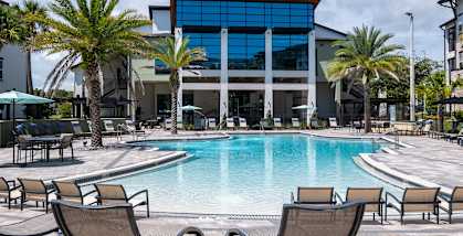 A large swimming pool surrounded by lounge chairs and palm trees.