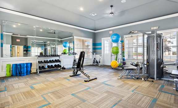 A gym with a variety of equipment including a squat rack, bench press, and a mirror.