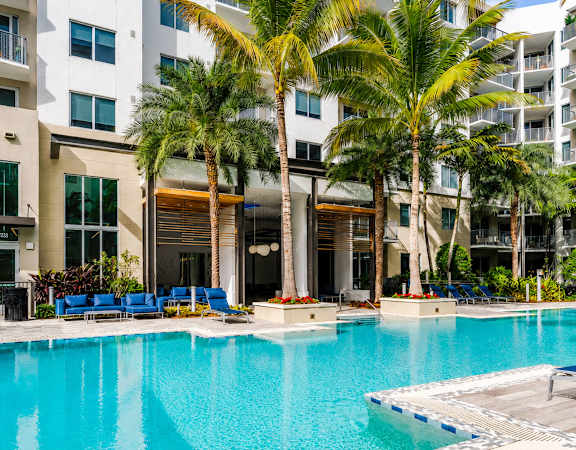 A large swimming pool in front of a building with palm trees.