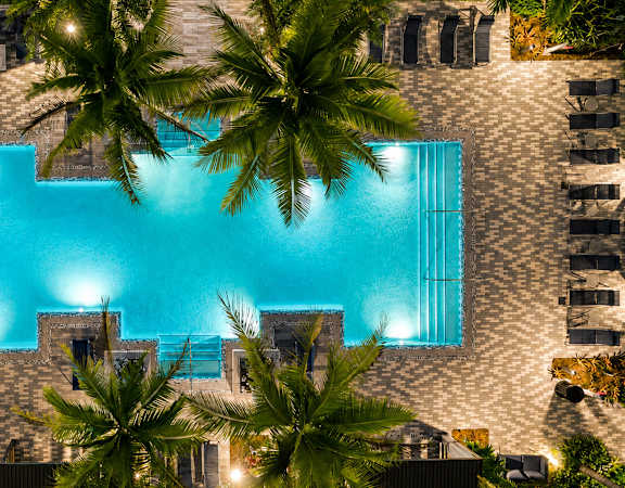 A swimming pool surrounded by palm trees and buildings.