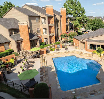 A swimming pool surrounded by a patio with chairs and umbrellas.